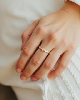 Hand wearing a gold ring with a soft focus background
